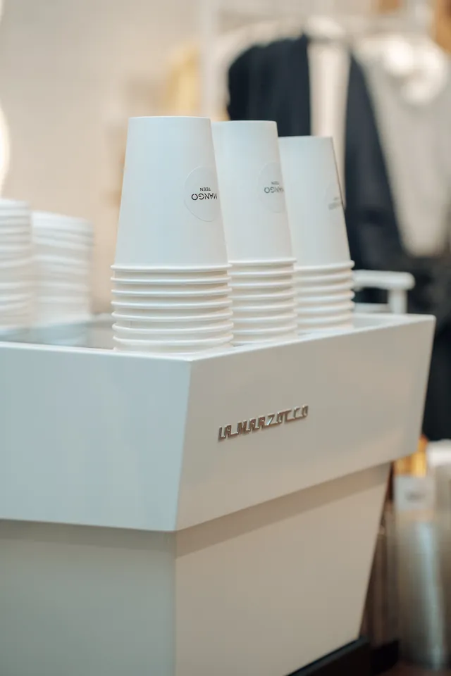 Gobelets blancs personnalisés Mango Teen empilés sur la machine espresso